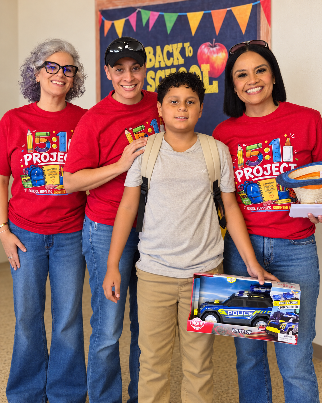 Volunteers in red Project shirts with a student in front of a Back to School banner