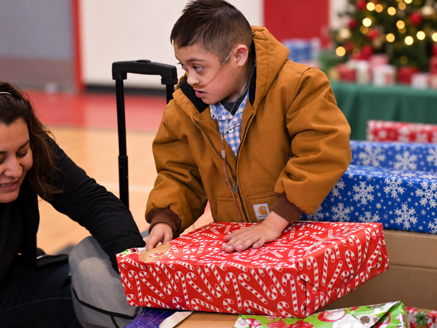 Boy helping with a wrapped Christmas gift during The 15:11 Project outreach