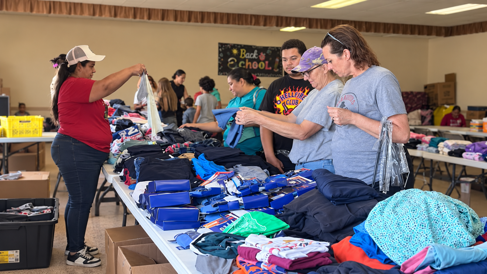 Volunteers sorting school clothing and supplies during a back-to-school outreach event