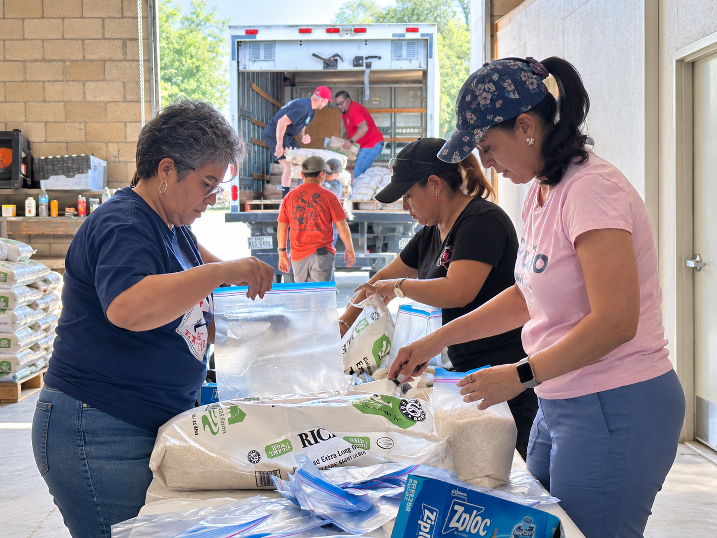 Volunteers bagging and packaging supplies in an outdoor work area